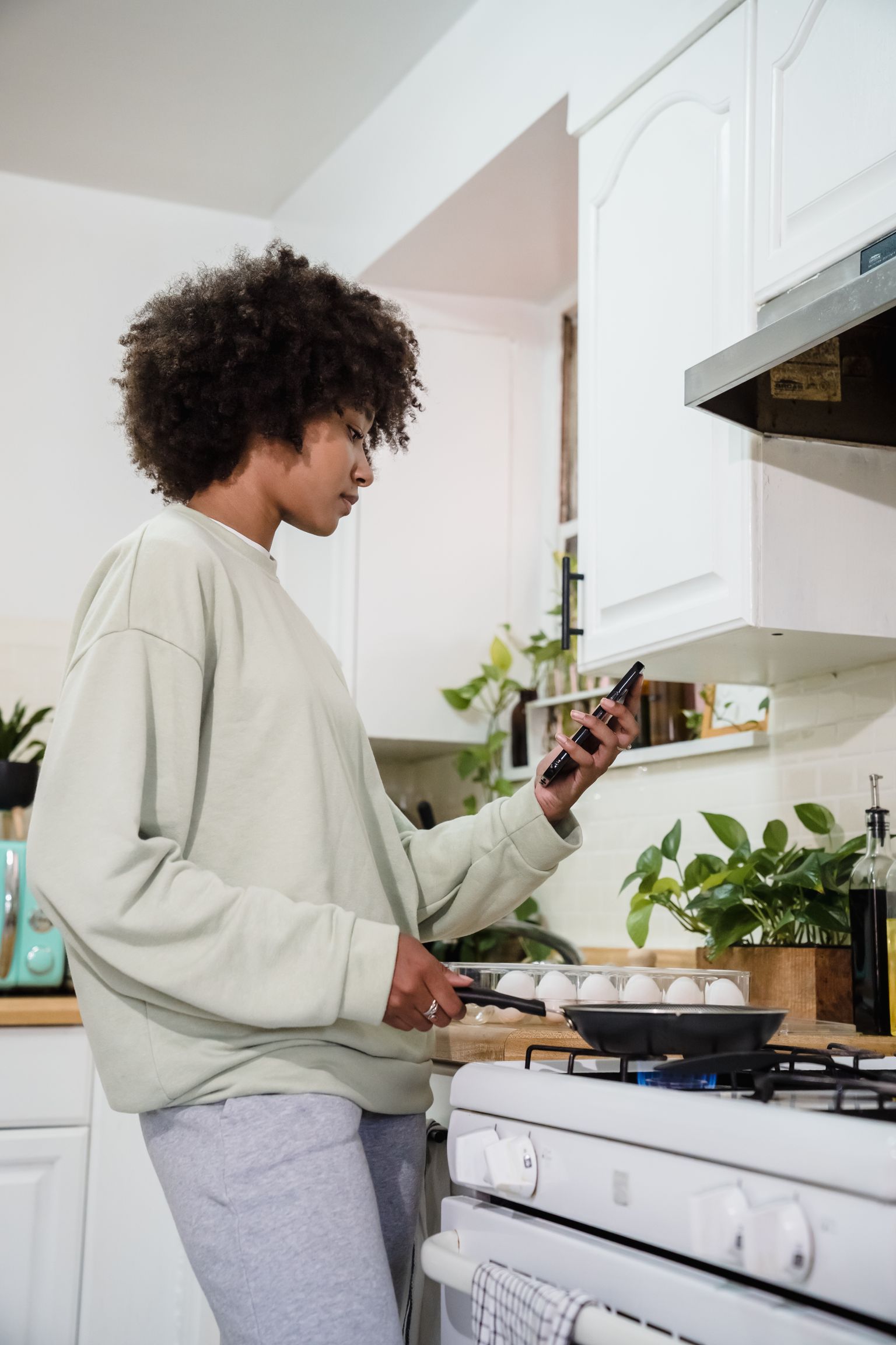 A woman checks her phone while preparing food in a real kitchen
