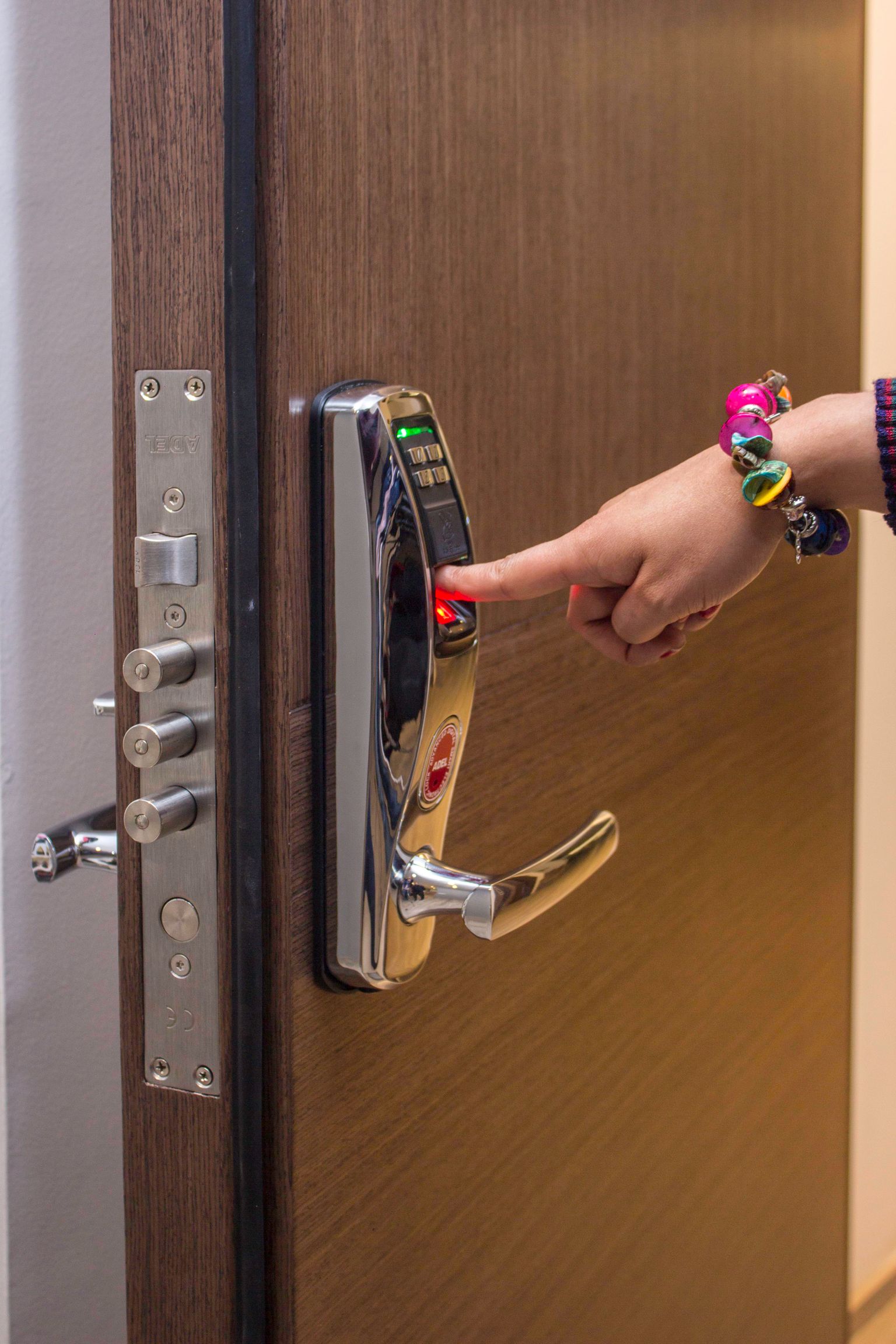 A hand using a fingerprint reader on a real electronic door lock